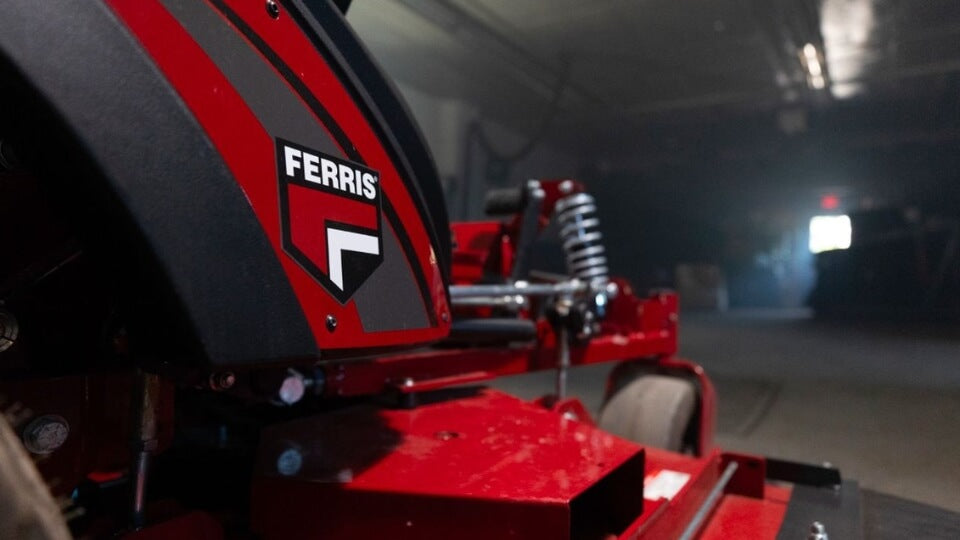 Garage scene and close up view of the red Ferris 300 S ride on mower showing the Ferris badge and suspension springs.