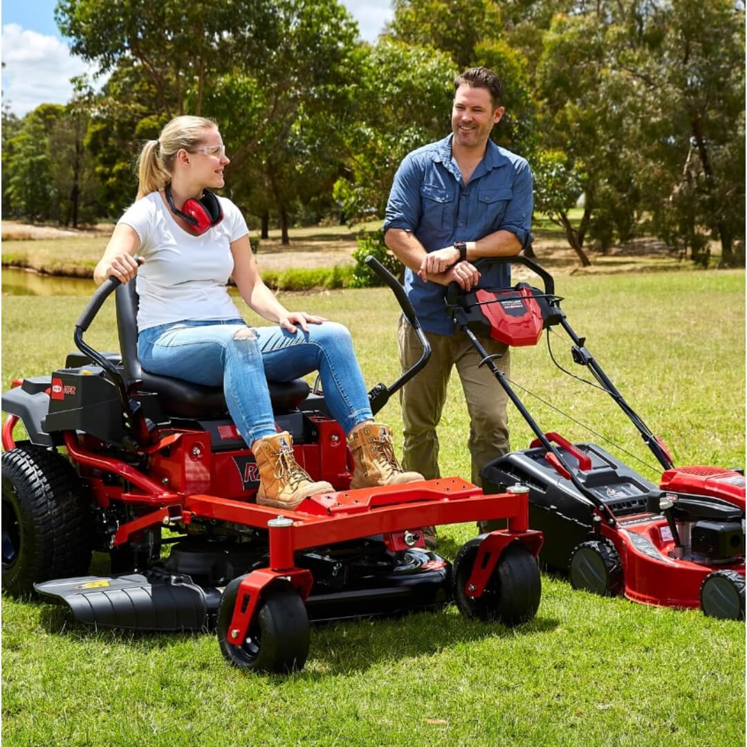 Man and woman with red Rover ride on mower and push mower.