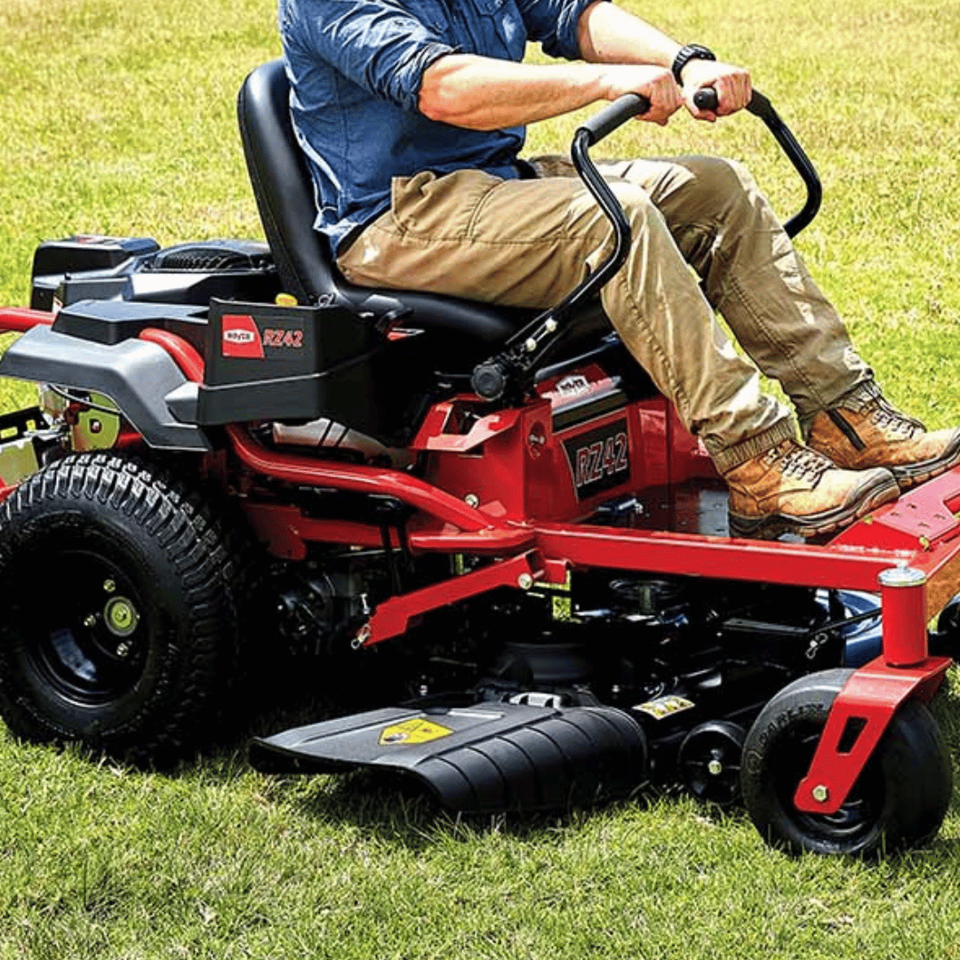 Person operating a red riding lawn mower on grass